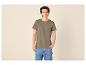 Jonge man in kaki T-shirt en blauwe jeans