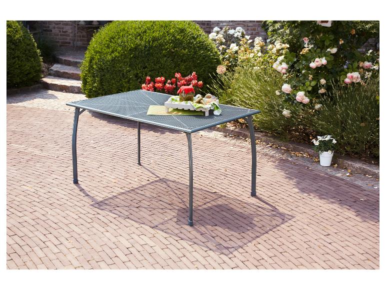 Grijze metalen tuintafel met potten en planten op een bakstenen terras.