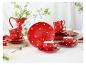 Rood servies met stippen, inclusief kopjes, borden en een kan op een witte tafel.