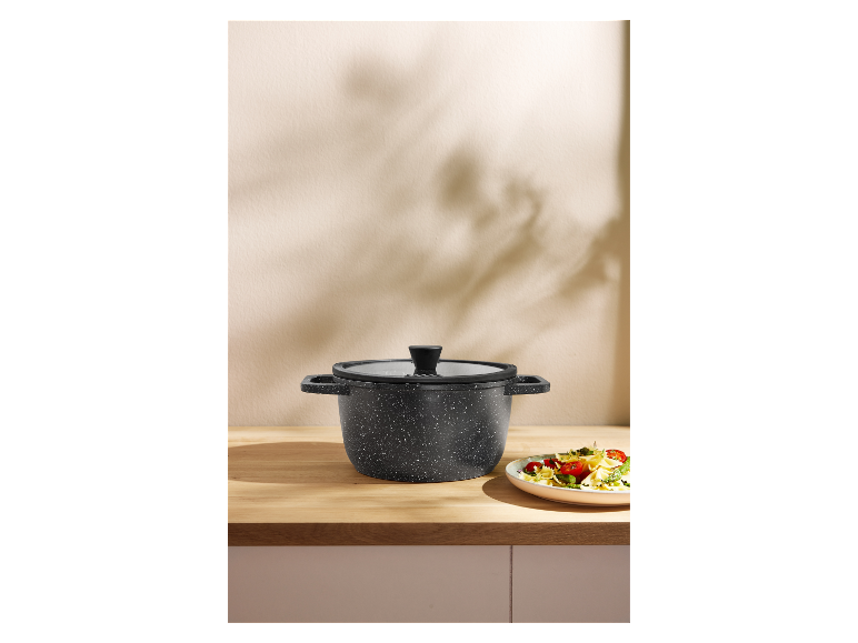 Donkere stenen potten met pasta op een houten aanrecht.