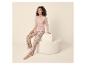 Vrouw in roze pyjama met bloemenprint en de tekst 'Stay Cozy' op een crèmekleurige poef.