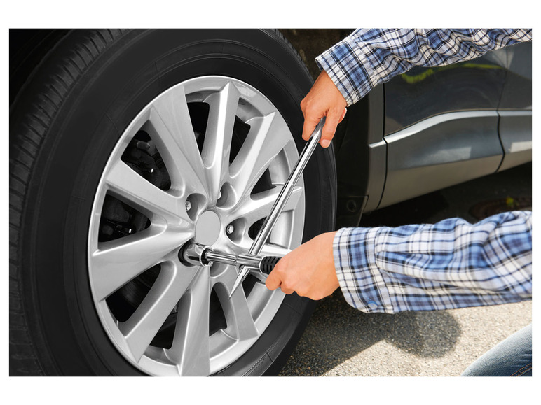 Een persoon gebruikt een momentsleutel om een wiel van een auto te bevestigen.