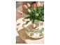 Roze en witte tulpen in een vaas met paaseieren op een houten tafel.