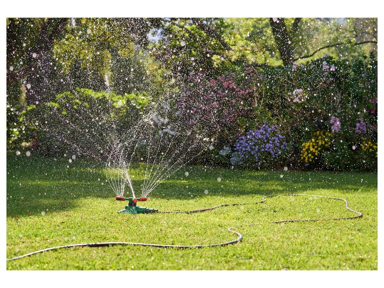 Een sproeier sproeit water op het gazon in de tuin.