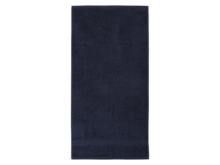 Een donkerblauwe, gevouwen badhanddoek op een witte achtergrond.