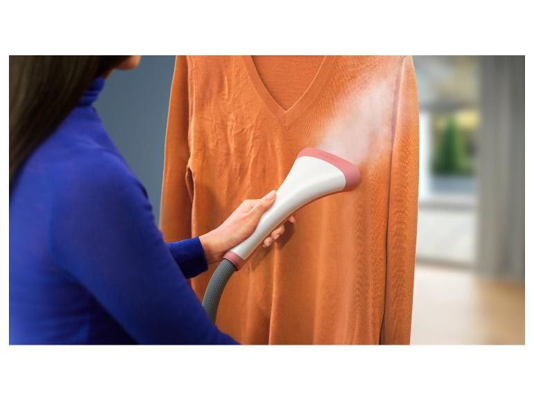 Een vrouw stoomt een trui met een stoomstrijkijzer.