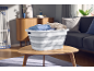 Opvouwbare wasmand met kleding op een houten salontafel in de woonkamer.