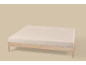 Lichtbeige hoeslaken op een houten bedframe.