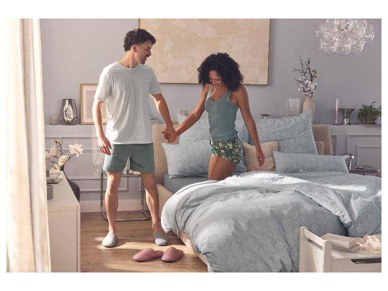 Man in ESMARA MEN herenpyjama houdt de hand vast van een vrouw op bed.