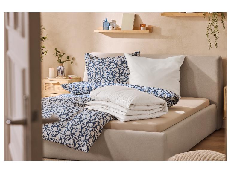 Gezellige slaapkamer met gestoffeerd bed, blauw bloemenbeddengoed en houten planken.