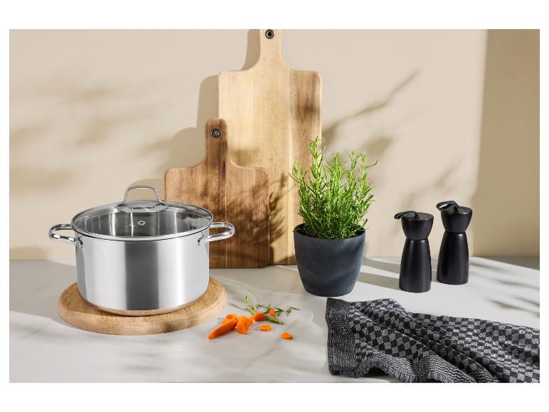 Roestvrijstalen pan met glazen deksel, houten snijplanken, rozemarijnplant en pepermolens.