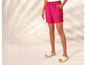 Vrouw draagt roze shorts en witte sandalen.
