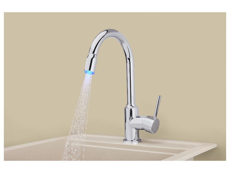 Chromen keukenkraan met uittrekbare sproeier en LED-licht, boven een beige spoelbak.