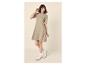 Lachende vrouw in een beige jurk met korte mouwen en witte sneakers.
