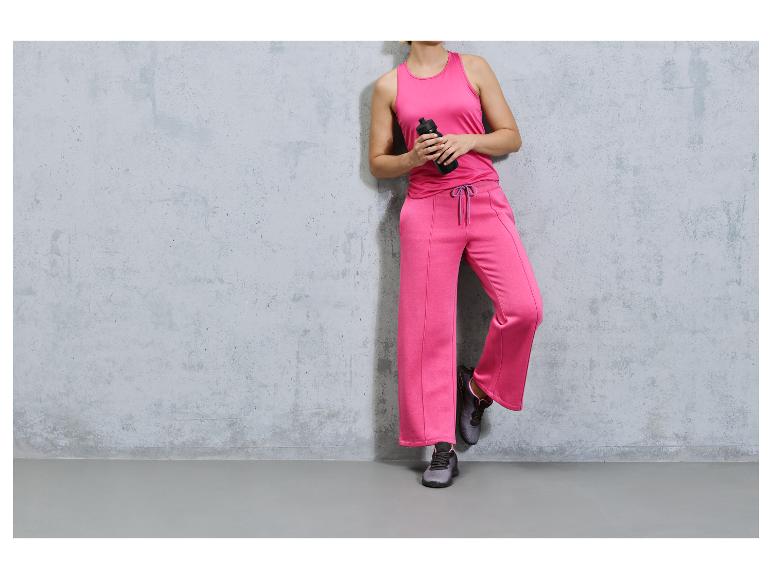 Een vrouw draagt roze sportkleding en zwarte sneakers