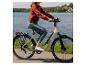Vrouw op elektrische fiets met meer en bos op de achtergrond