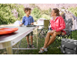 Vrouw en kind kamperen met een klaptafel, campingstoelen en tenten.