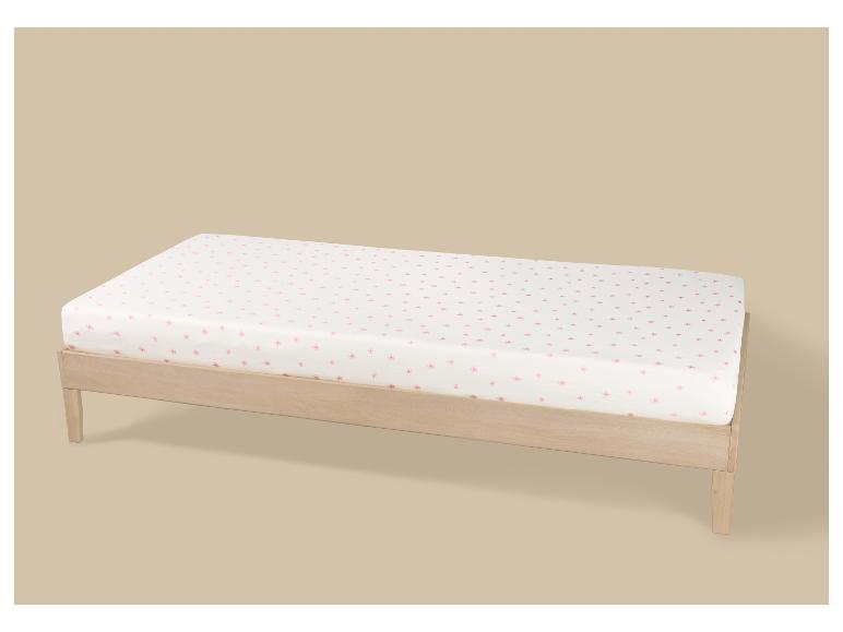 Licht houten eenpersoonsbed met wit matras en roze bloemenpatroon