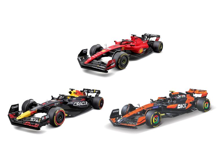 Drie speelgoed raceauto's, één rood, één zwart en geel, en één oranje en zwart.