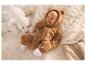 Baby in berenpak, liggend op een zachte deken met knuffels.