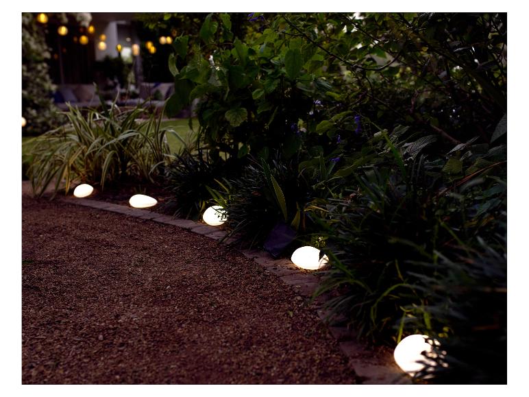 Zonne-aangedreven stenen lampen verlichten een tuinpad.