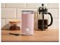 Roze koffiemolen, cafetière en gemalen koffie op een houten aanrecht.