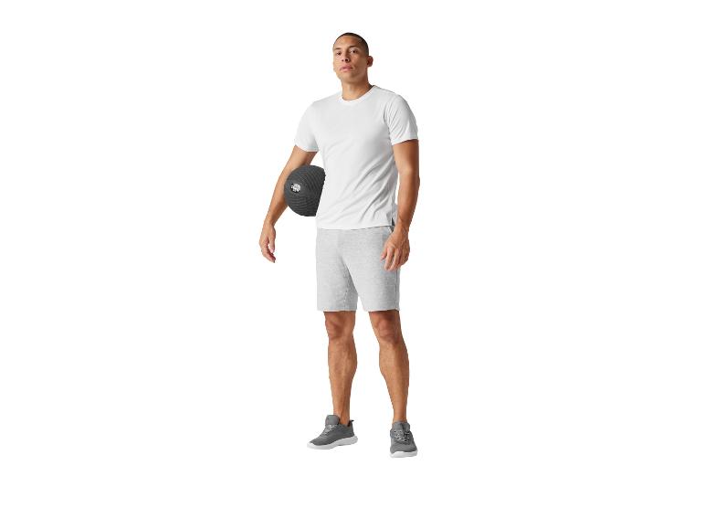 Man in t-shirt en korte broek met een fitnessbal.