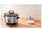 Slowcooker met stoofpot op een houten aanrecht in de keuken.
