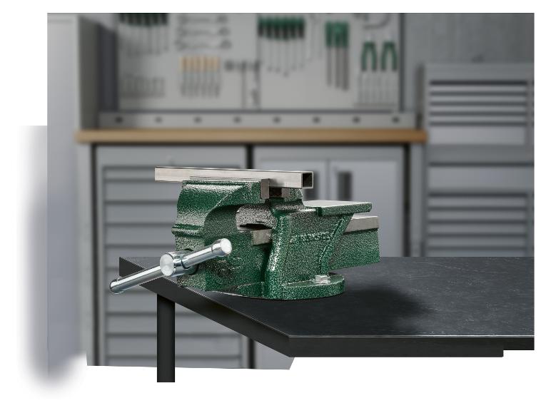 Groene bankschroef met een vastgeklemd metalen stuk, op een werkbank in een werkplaats.