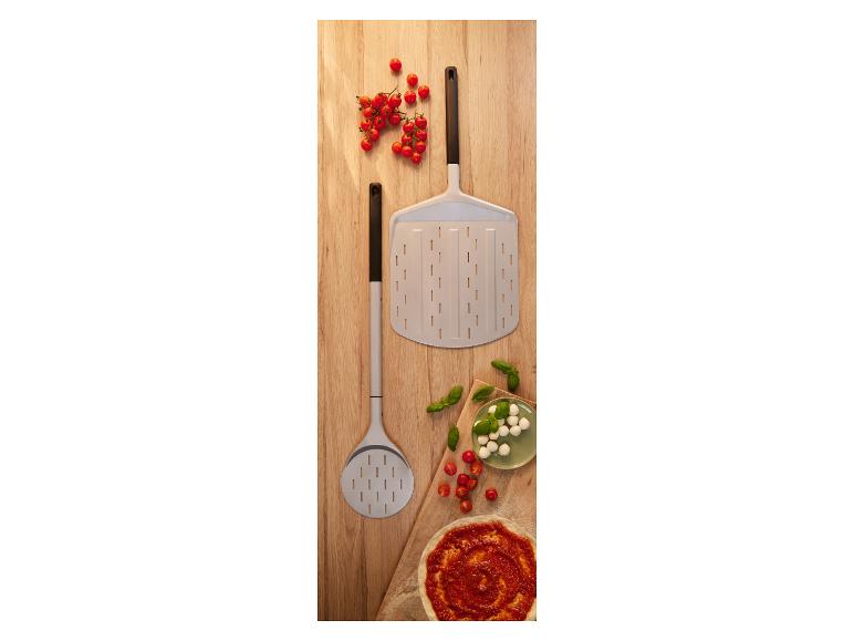 Pizzaschoppen met cherrytomaten, mozzarella, basilicum en pizzabodem op een houten plank.