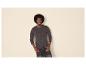 Man met afro draagt een donkergrijs Henley-shirt met lange mouwen en een donkere jeans.