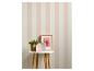 Gestreept behang in roze en wit met een plant, fotolijst en decoratieve huisjes op een tafel.