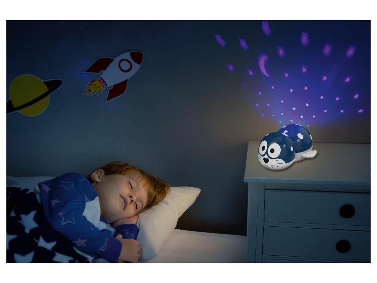Een kind slaapt in een bed met een zeehond nachtlamp projector die sterren en manen projecteert.