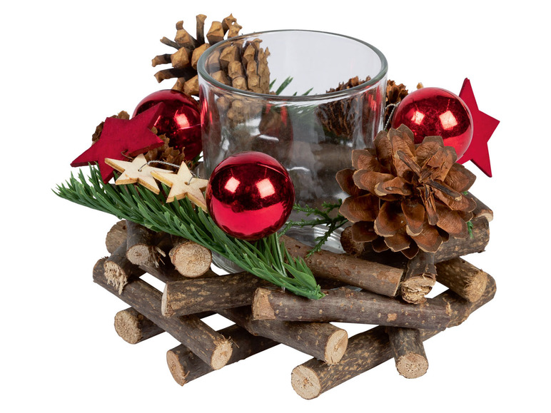 Kerstdecoratie met een glazen kaarshouder, dennenappels en rode kerstballen.