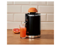 Zwarte citruspers met grapefruit die sap in een glas perst op een houten oppervlak.