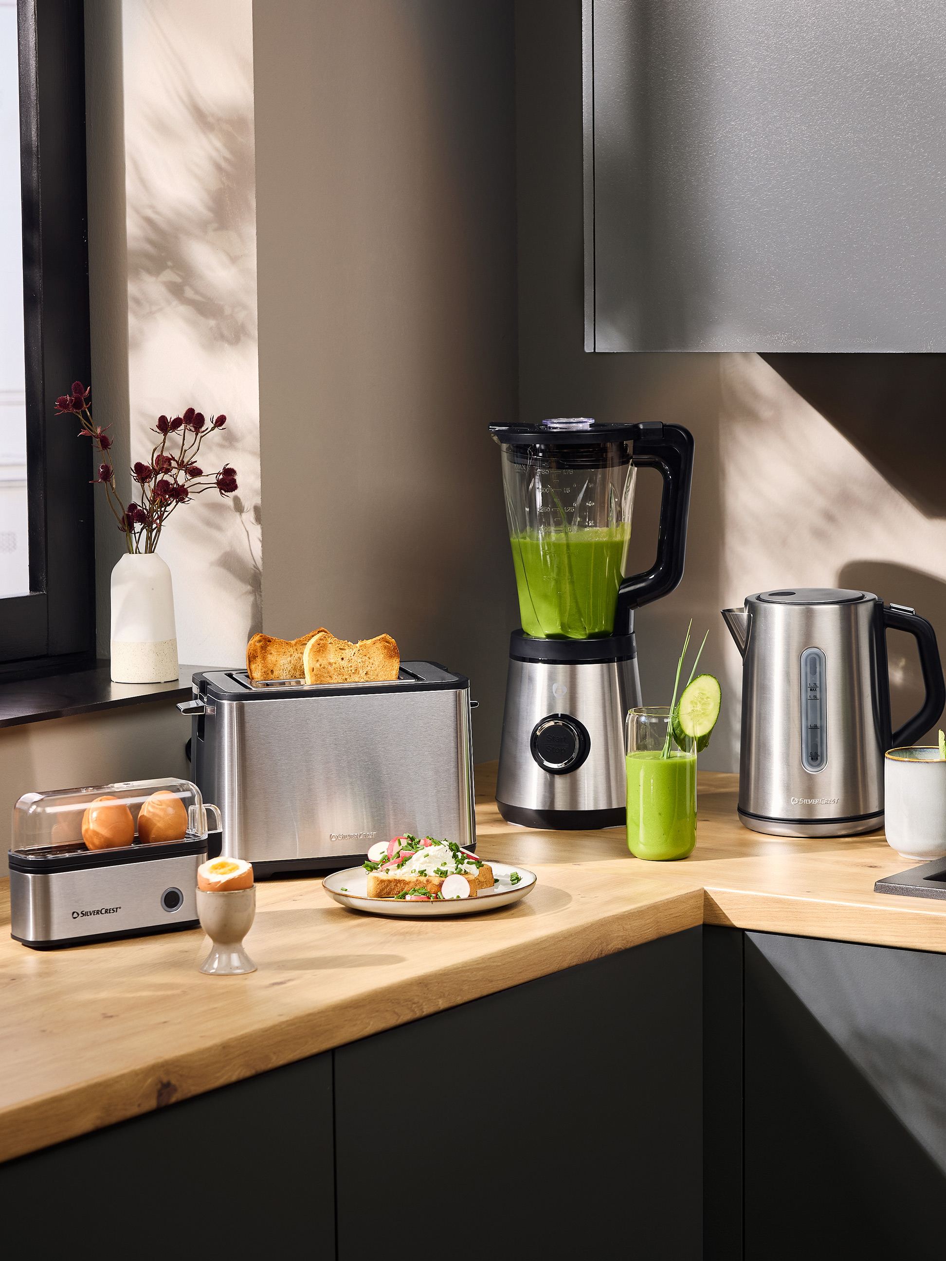 Broodrooster, blender en waterkoker in een moderne keuken met ontbijt.