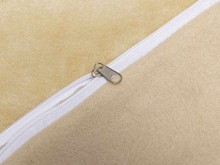 Een beige wollen deken met een witte rits.