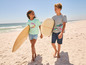 Twee kinderen lopen op het strand met surfplanken.