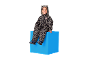 Kind in luipaardprint overall met oren, zittend op een blauwe kubus.