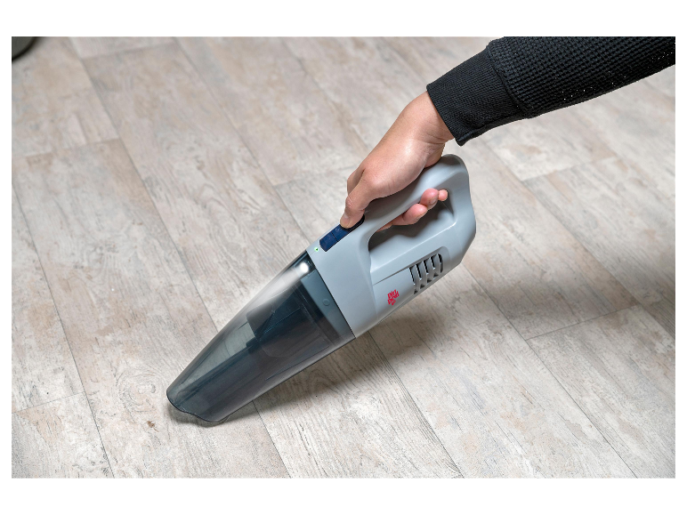 Een hand houdt een Dirt Devil handstofzuiger vast om de vloer te reinigen.