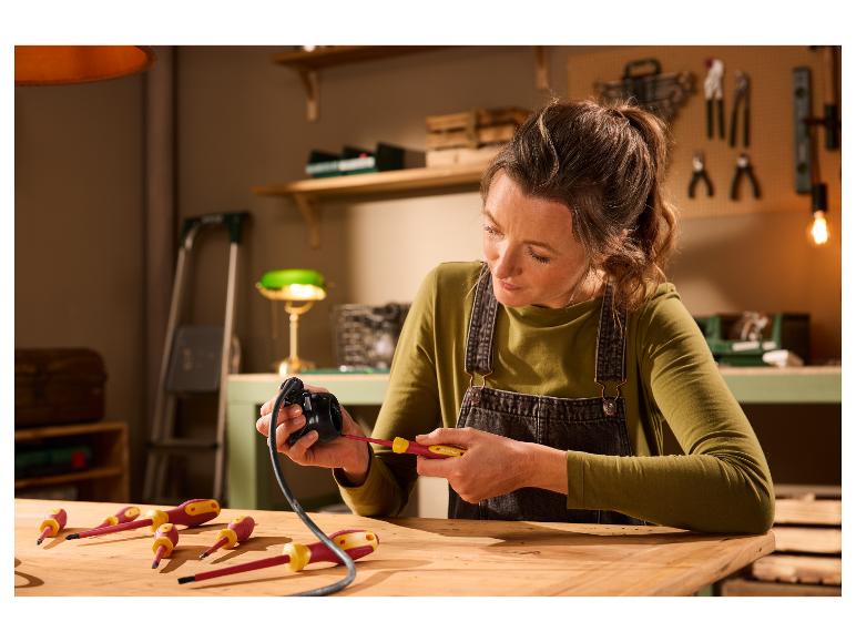 Vrouw gebruikt een Parkside schroevendraaier om een elektrisch apparaat te repareren op een houten werkbank.