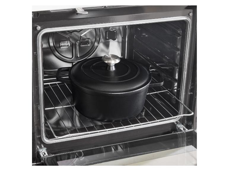 Zwarte gietijzeren braadpan in een oven op een rooster.