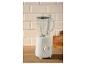 Witte blender met glazen kan op een houten aanrecht met lichte tegels op de achtergrond.