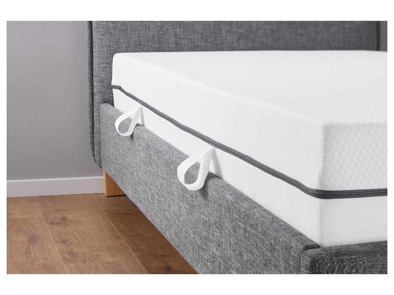 Een grijs bed met matras en houten poten.
