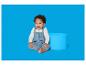 Baby in blauw gebreid rompertje zit naast een blauwe cilinder.
