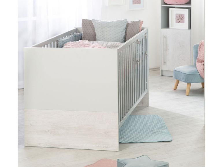 Een babybed met houten details en een zacht blauwe mat.