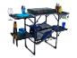 Een opklapbare campingtafel met een fornuis, een koelbox en serviesgoed.