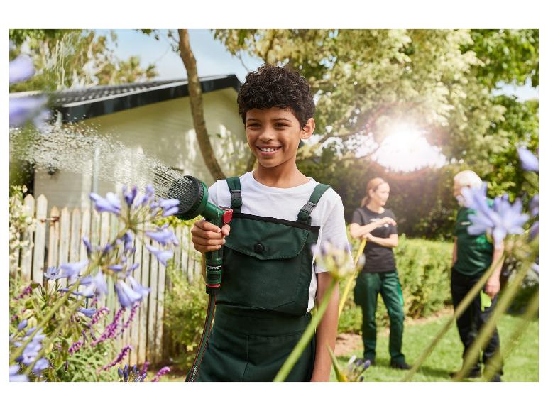 Een kind sproeit bloemen met een Gardena gieter in de tuin.