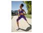 Vrouw in paarse sportbeha en capri-legging rekt zich buiten uit.