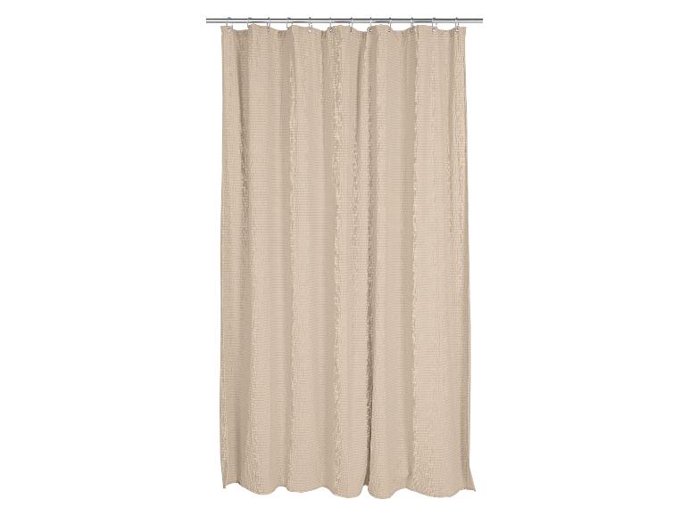Beige douchegordijn met een getextureerd wafelpatroon, hangend aan een zilveren stang.